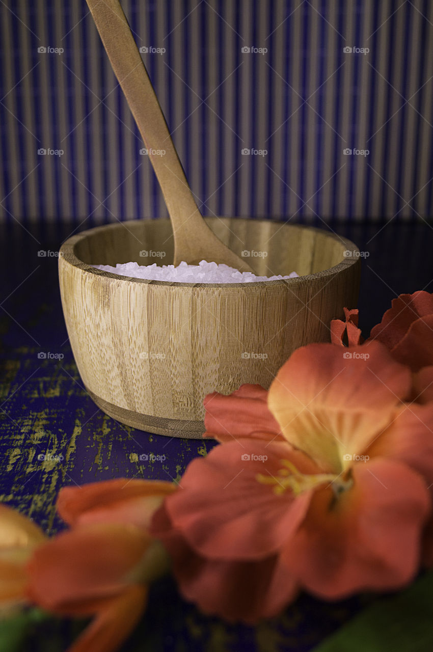 salt in bamboo bowl with tropical flowers and rustic background