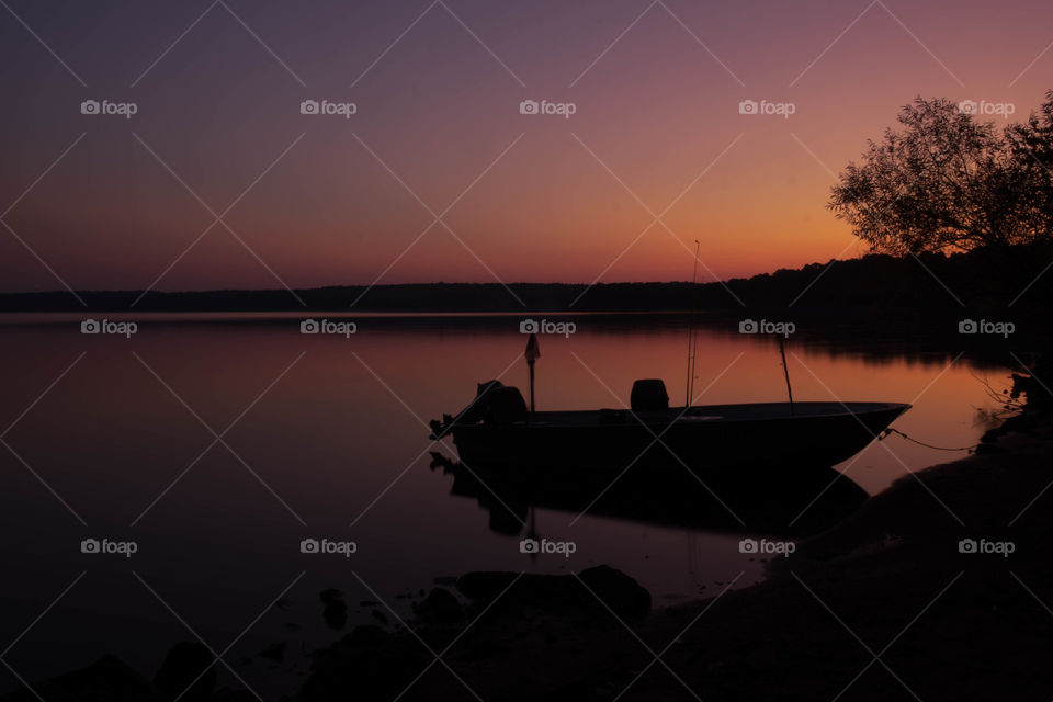 Foap, Silhouettes and Shadows: A tied boat floats perfectly still during the vivid twilight period just before sunrise. Rollingview if Falls Lake State Park near Raleigh North Carolina.