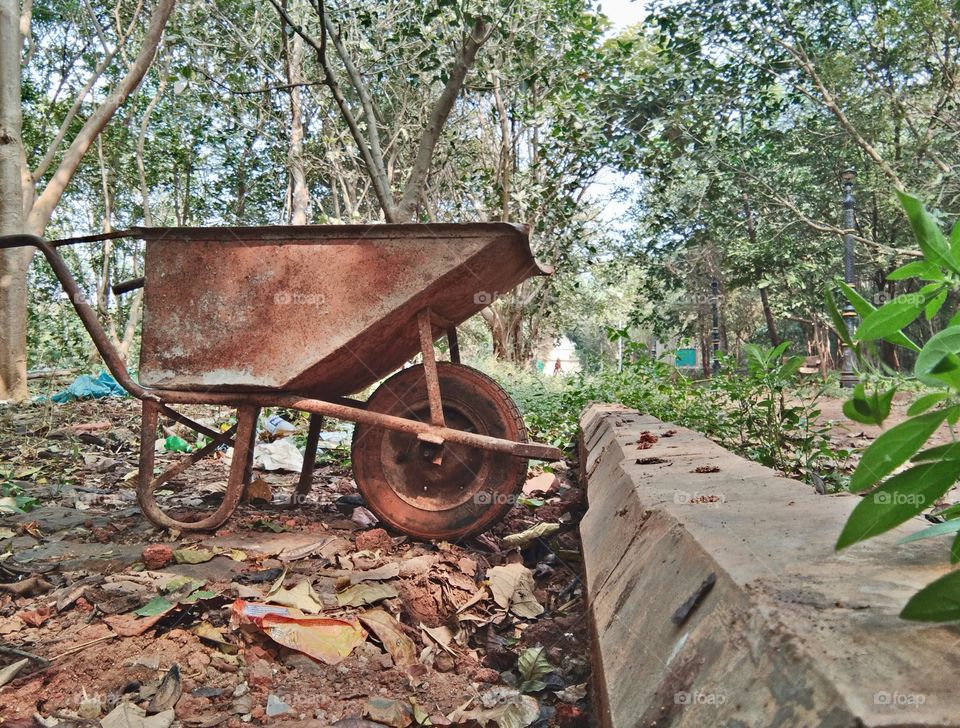 Gardening tools or equipment and construction tools, old rusty wheelbarrow or construction trolly in garden having tree background.