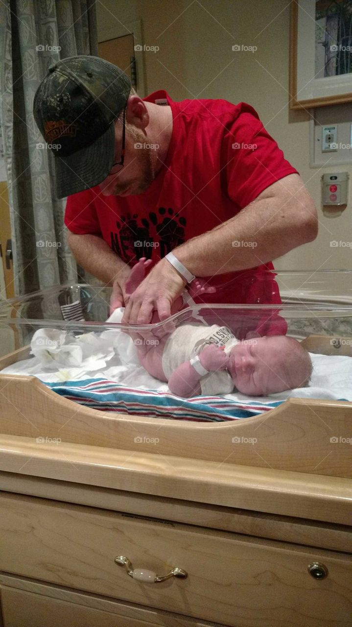 dad changes first diaper on new son.
