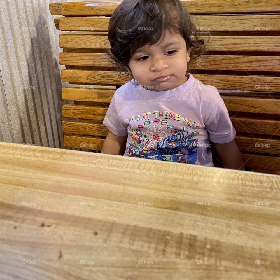 Toddler sitting at table disgusted with food, Childs face showing emotion, toddler is disgusted, toddlers face shows disgust for food, not having fun at the restaurant