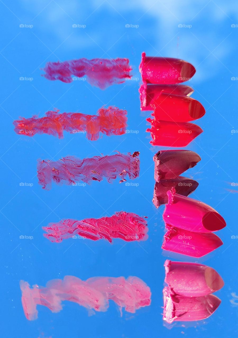 On the mirror surface, there are brushstrokes and lipsticks to them in five colors: dark red, three shades of red and pink. It also reflects the blue sky with a white cloud