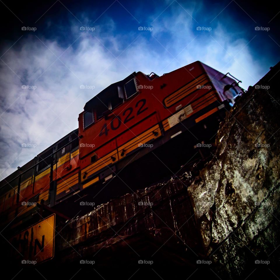 bnsf roaring on the tracks above against a cloudy sky
