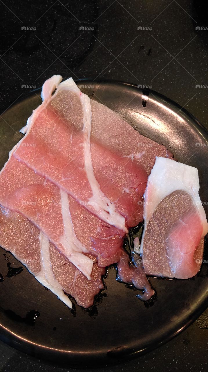 Raw slice beef on the black dish.