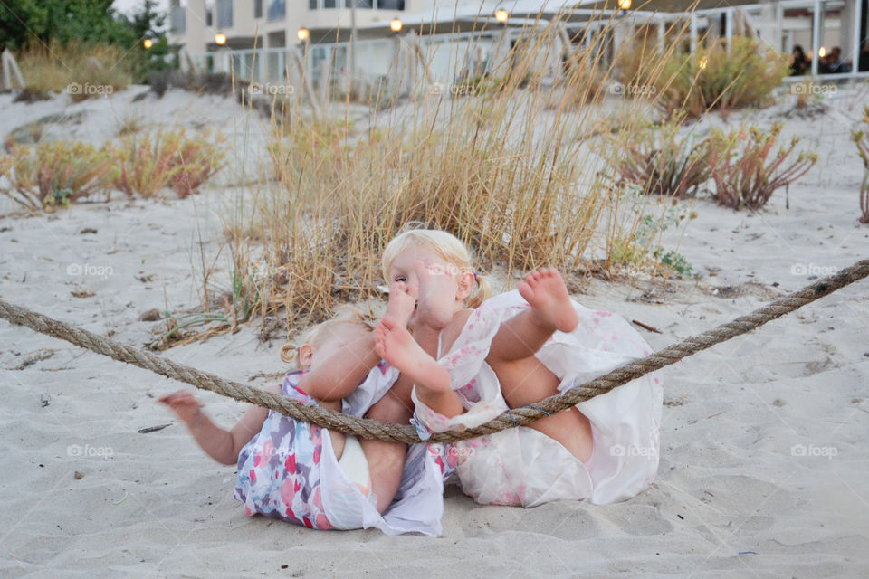 Two young sisters enjoying the beach falling down on the sand. Alcudia, Majorca,
This picture is on of three pictures were the both fal back in the sand.