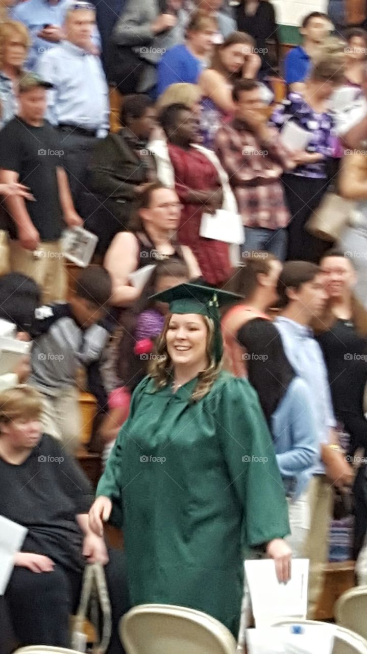 Happy graduate woman walking in crowd of people