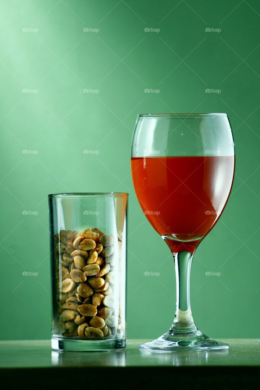 goblet of red wine and peanuts in a glass