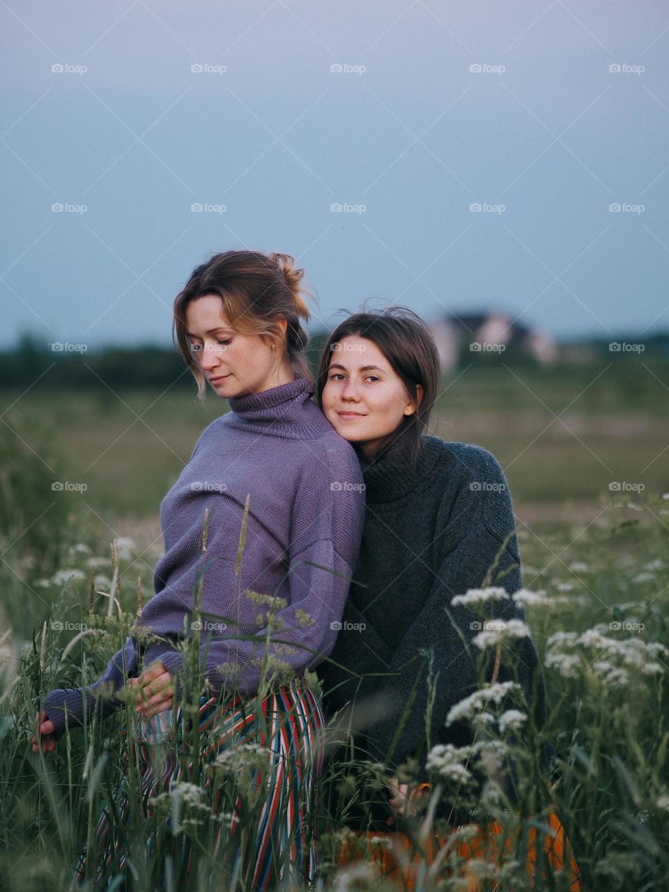 Beautiful girlfriends in the blooming field in summer day
