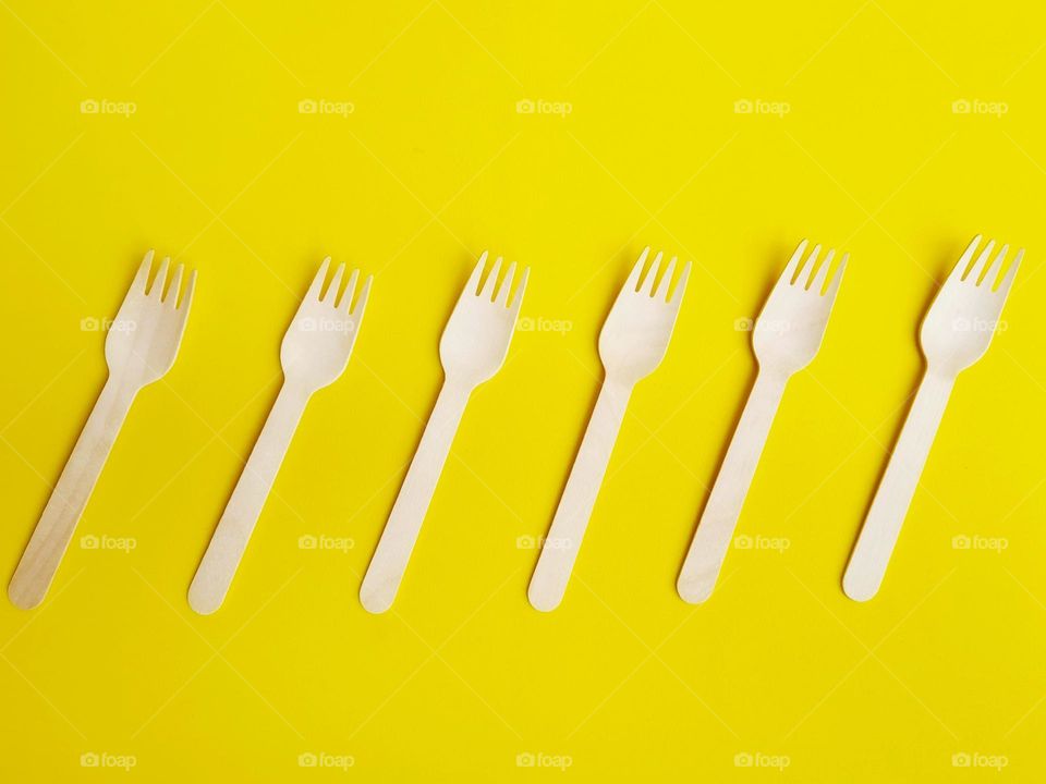 wooden ecological forks stand in a row on a yellow background