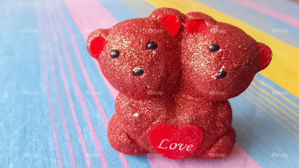 A pair of teddy bears placed on a colorful table.