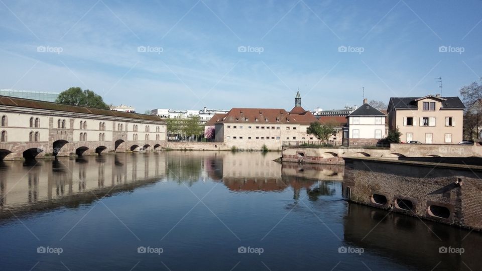 Strasburg's architecture bordered with bright blue sky and clear river whitch reflects everything above it.