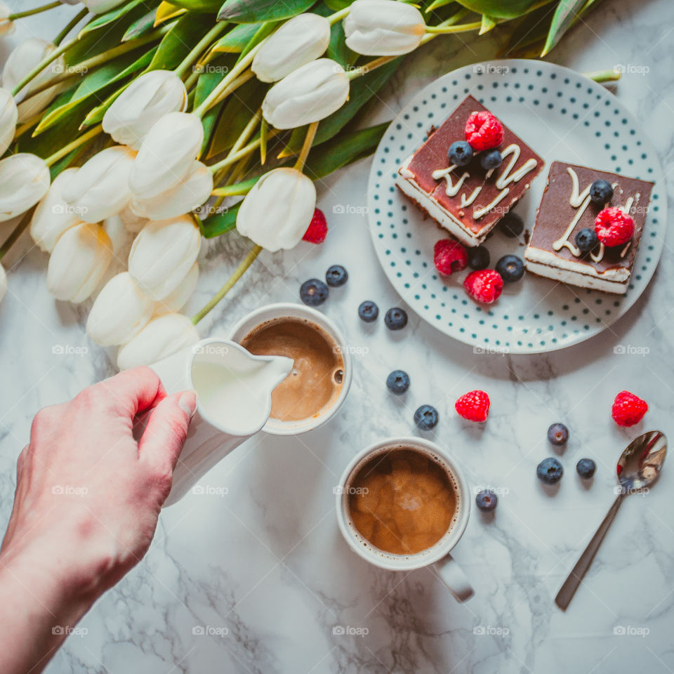 Person pouring milk in coffee