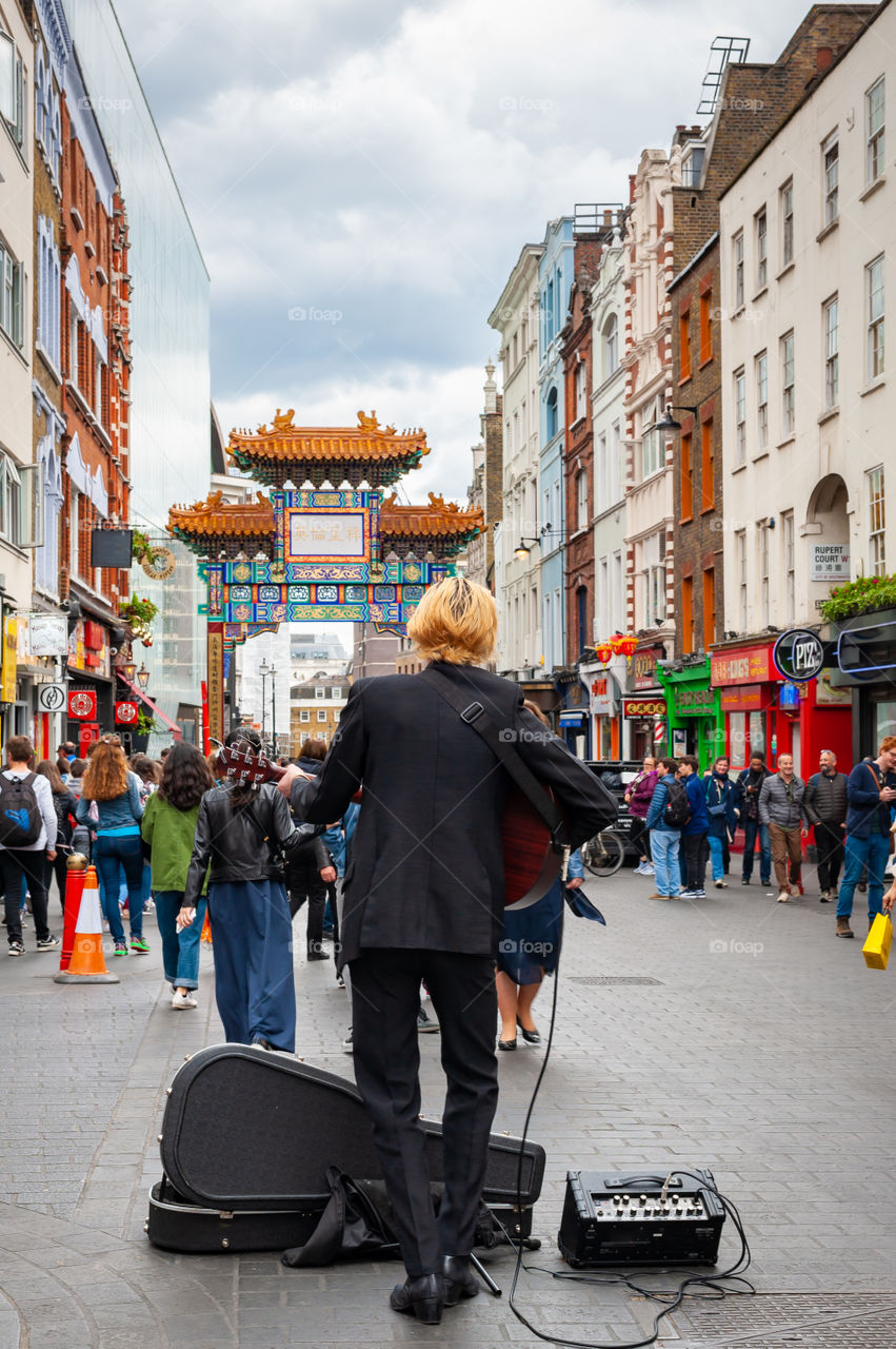 Street musician performing in Soho district known as the London Chinatown. London. UK.