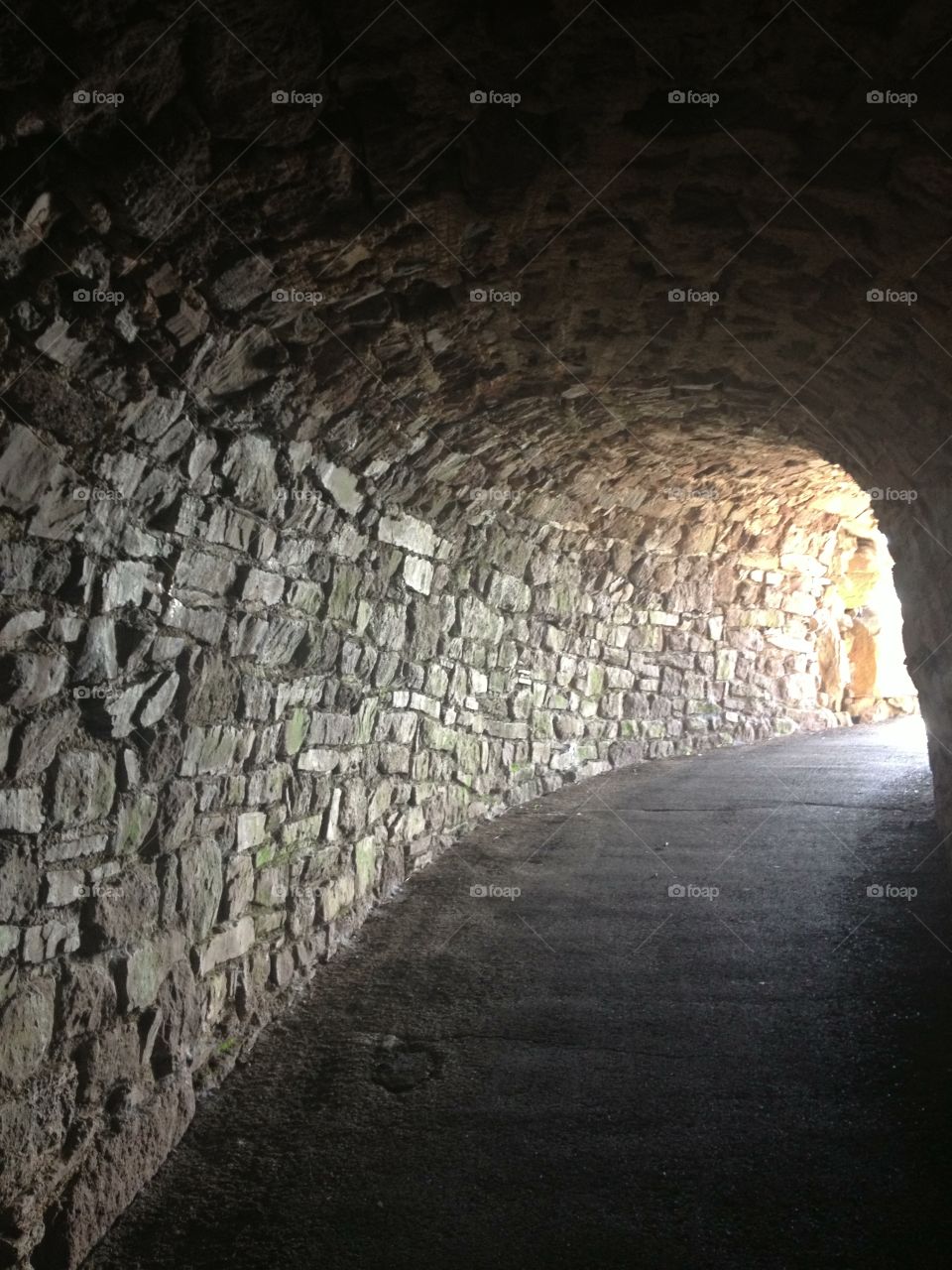 Daylight. Light at the end of the tunnel.  Flagstone path winds along a stonework tunnel.