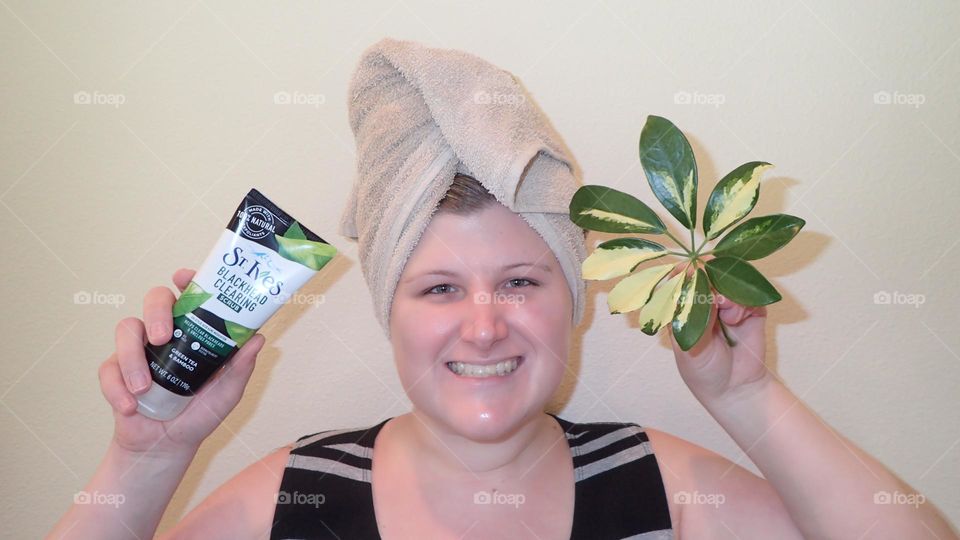 Young blonde woman holding fresh out of shower product towel on head