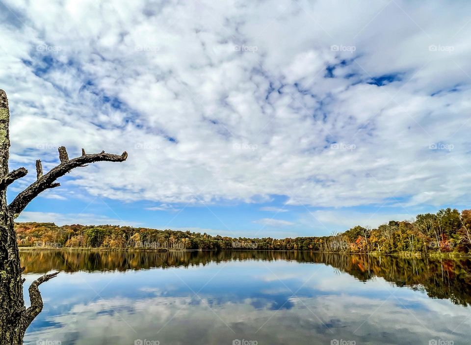 Beautiful autumn day with red fall foliage and reflections of the clouds and sky.