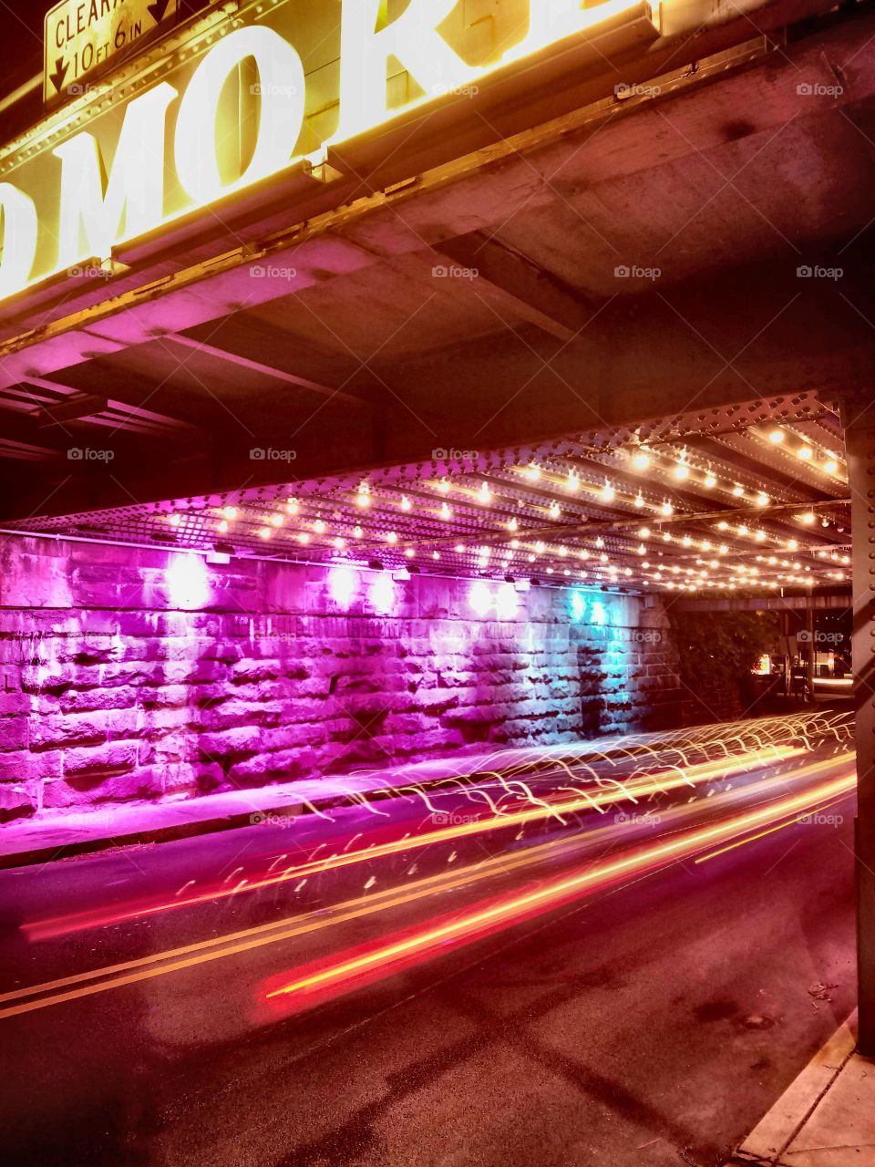 light trails from traffic under colorful train underpass
