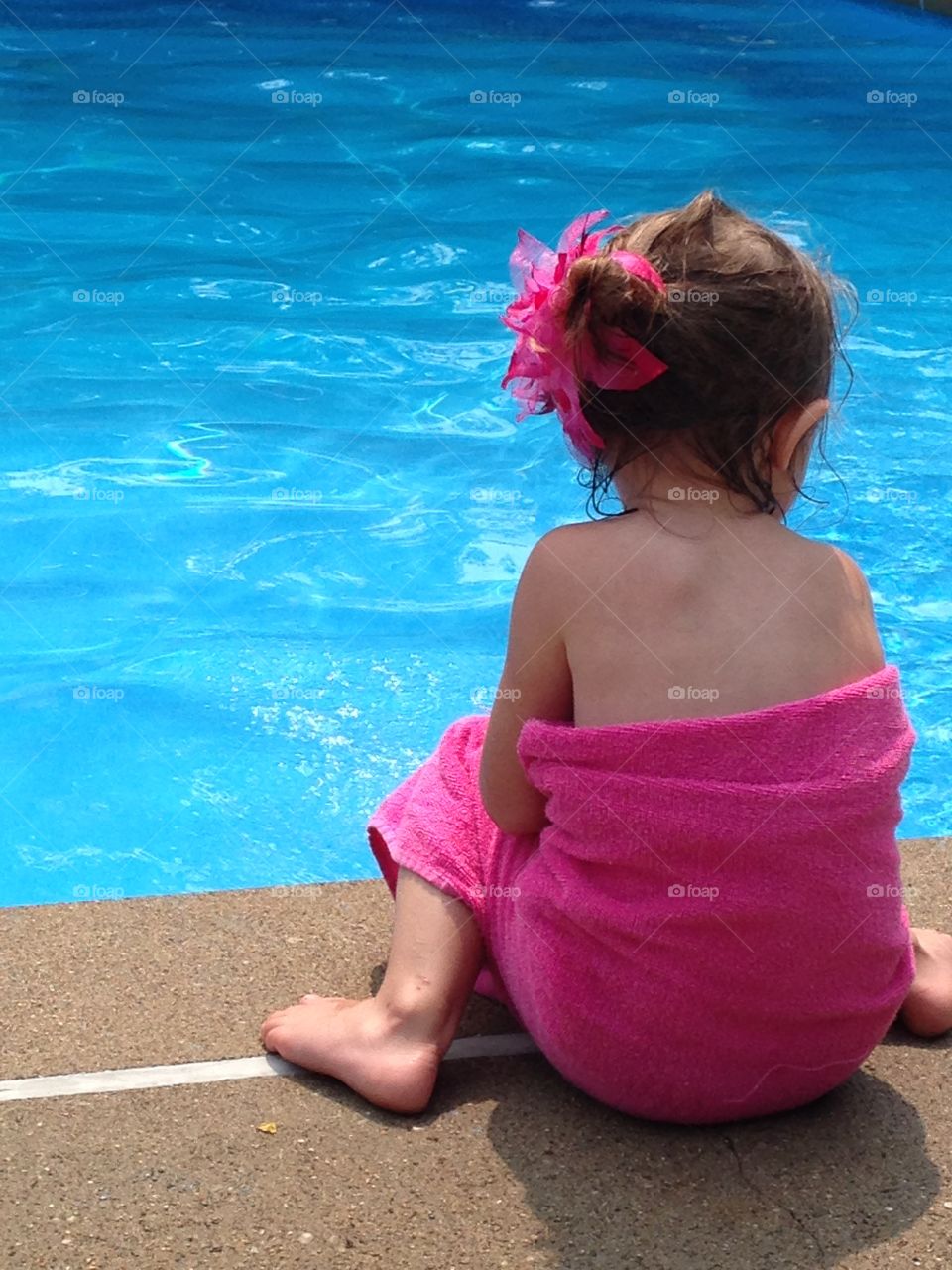 Little girl sitting by pool
