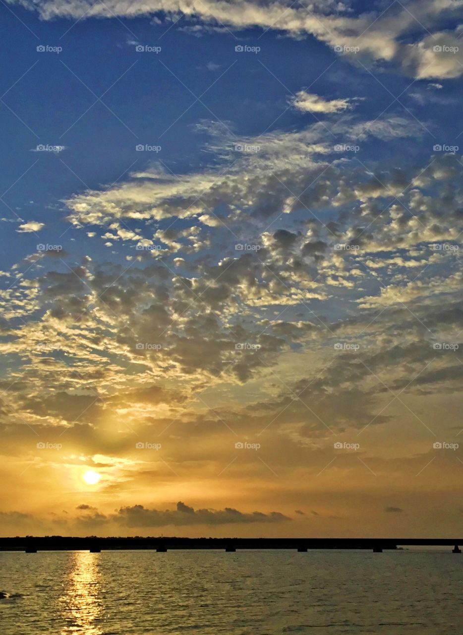 Beautiful floating clouds blend in with the golden sunset. The setting sun symbolizes the completion of a journey. This journey could be life itself. 