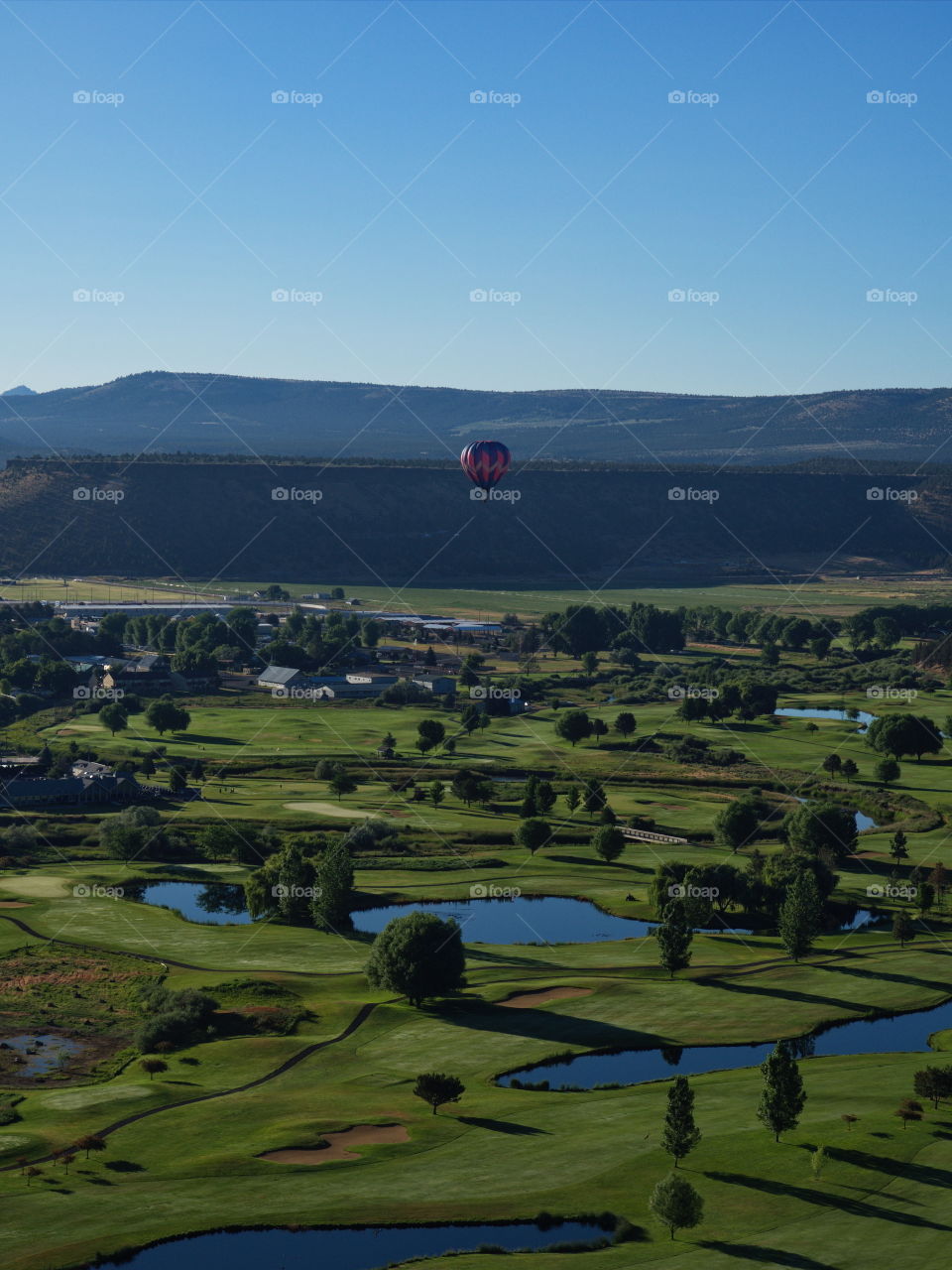 View from the Ochoco State Scenic Viewpoint of the town of Prineville, home of a growing technology industry, in Central Oregon with hot air balloons in a smoky sky from seasonal forest fires. 