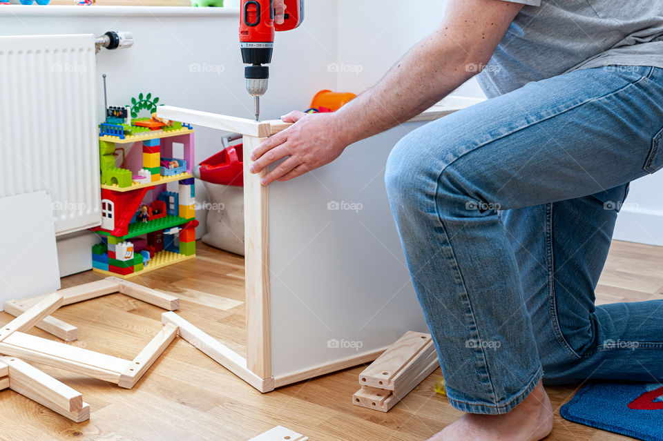 Father setting up a flat pack desk furniture for child's bedroom.