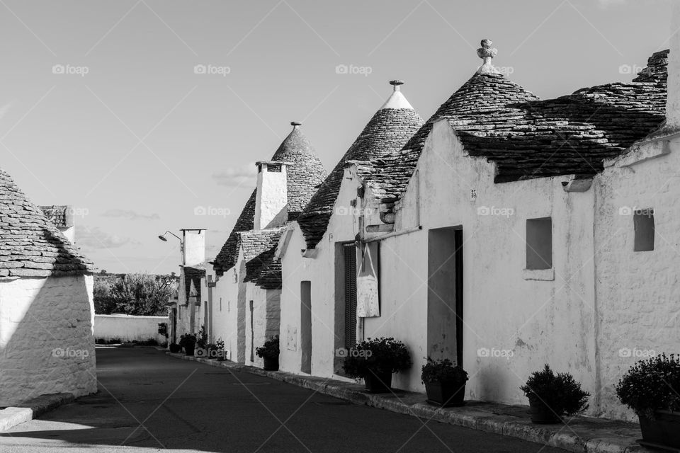 Beautiful side view of unusual creative stone prefabricated round trulla houses with rectangular doorways, square windows and conical roof in Alberabello city in Italy, close-up side view. Architecture concept of ancient creative houses.