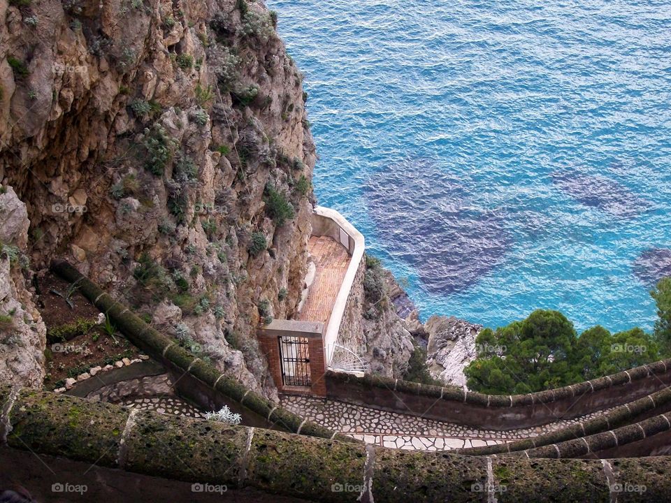 A closer view of the crystal clear blue waters off the island of Capri over looking its mosaic path down the cliff side