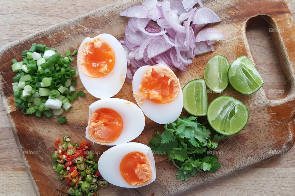Asian Ingredients for Thai menu: boiled egg spicy salad lying on old wooden chop board preparing to mix - top view