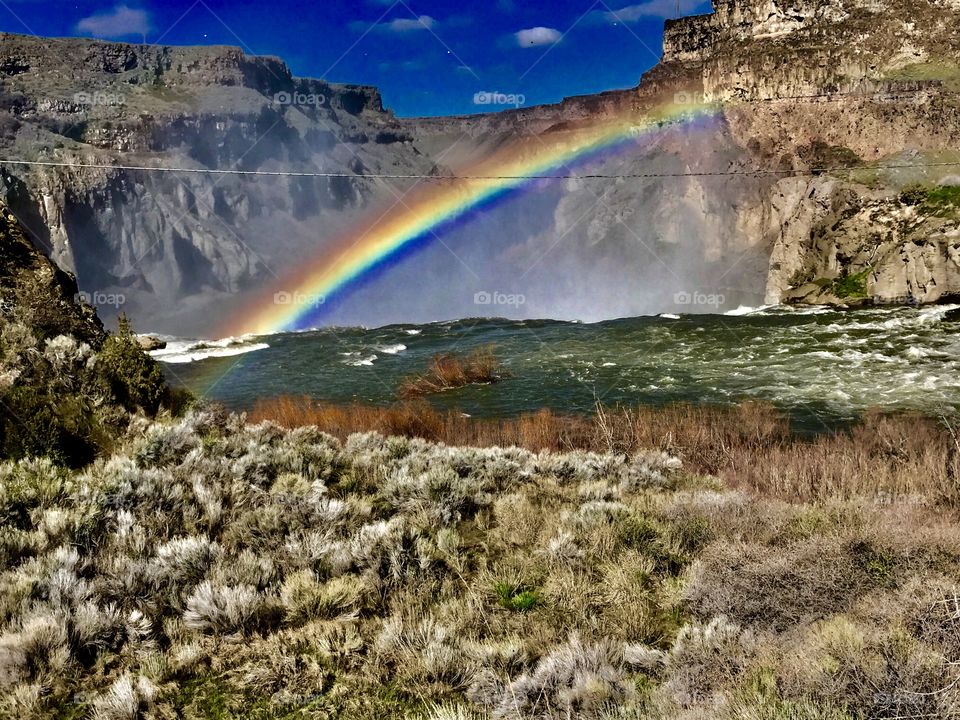 Vibrant rainbow, river and rock