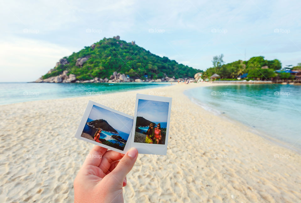 Hand holding photographs at beach