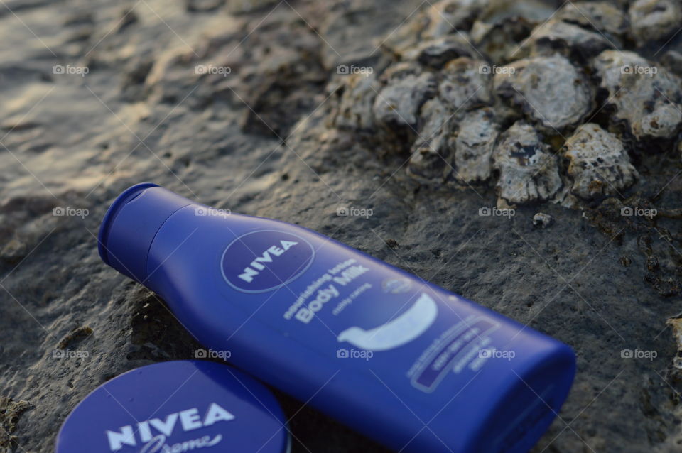 Nivea creme and Nivea body lotion are flaunted on the sea rock covered by beautiful Leathesia or Marine algae.