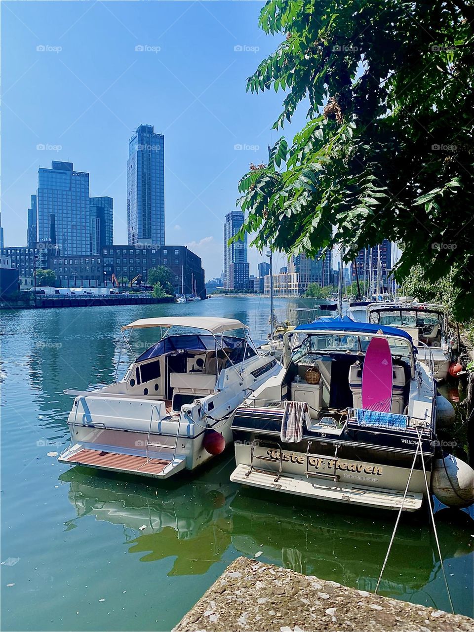 This is the familiar view of „Newtown Creek“ in LIC, Queens with its variety of boats tied to the shore seen from the waterfront edge of the parking lot beneath the „Pulaski Bridge“ and views all the way to „Manhattan“. 2023. Hypnotic Productions