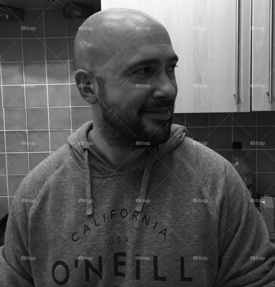Husband chilling out in the kitchen. Handsome bald man in black and white candid shot. Natural. 
