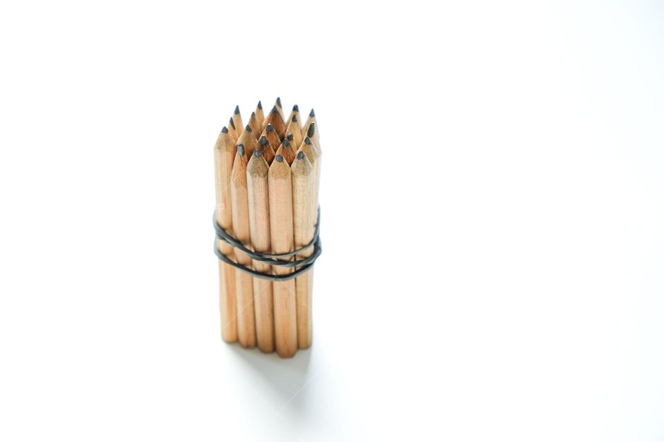Bunch of simple wooden pencils standing on white background