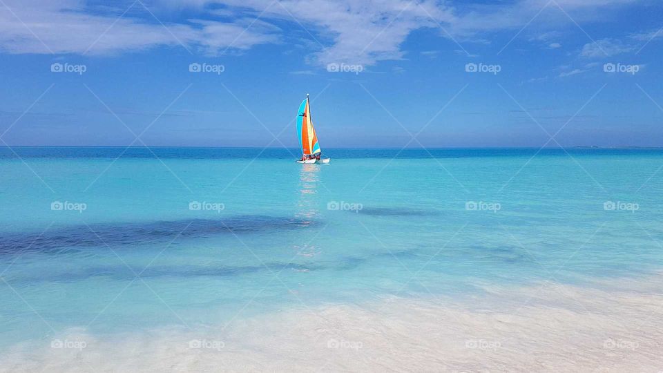 A sailboat on the ocean. Turquoise water and blue sky