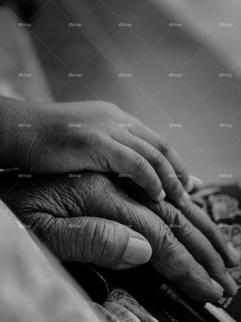 A very elderly grandmother and grandson hold hands with each other showing a love relationship.