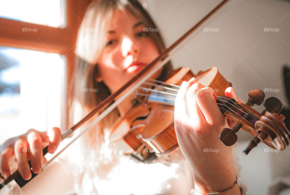 A girl play the violin in the house