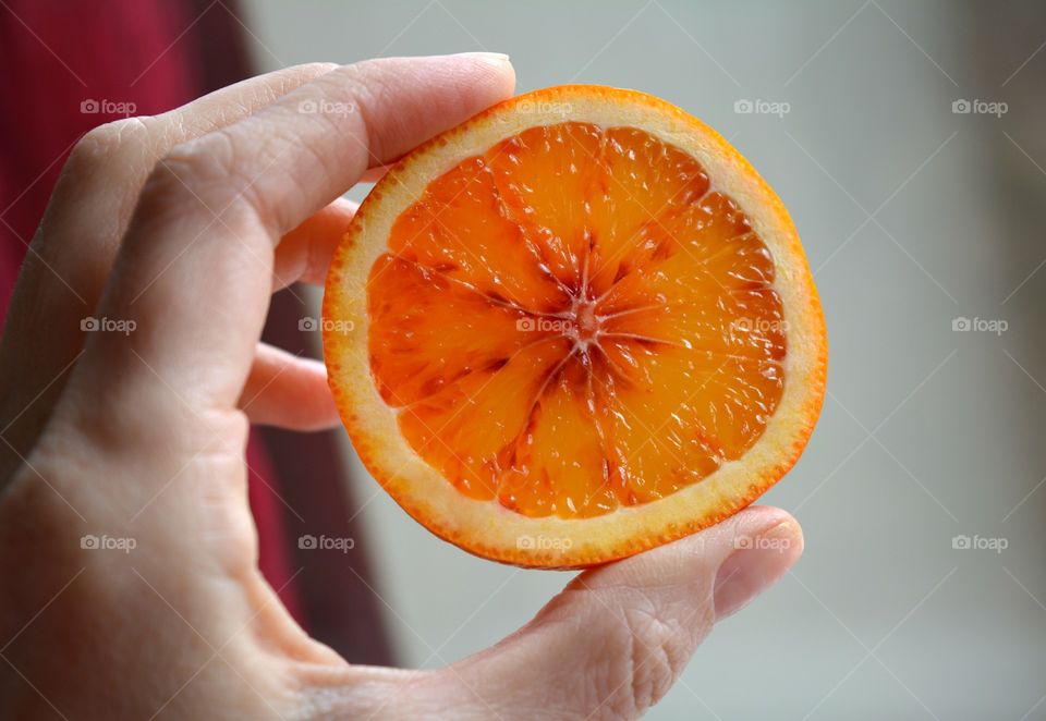 Close-up of human hand holding half of orange fruit