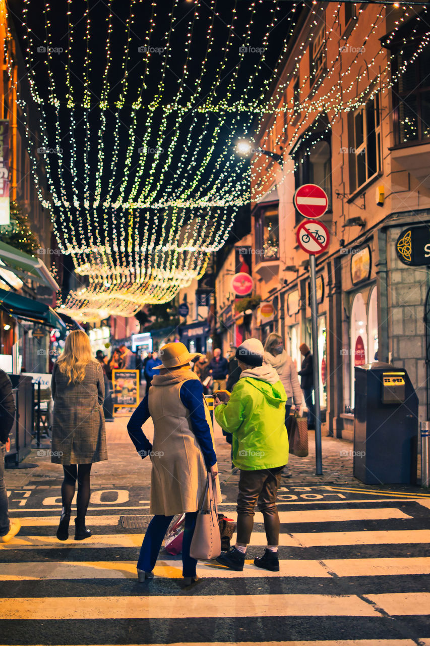 Ladies standing on the street under Christmas decorations