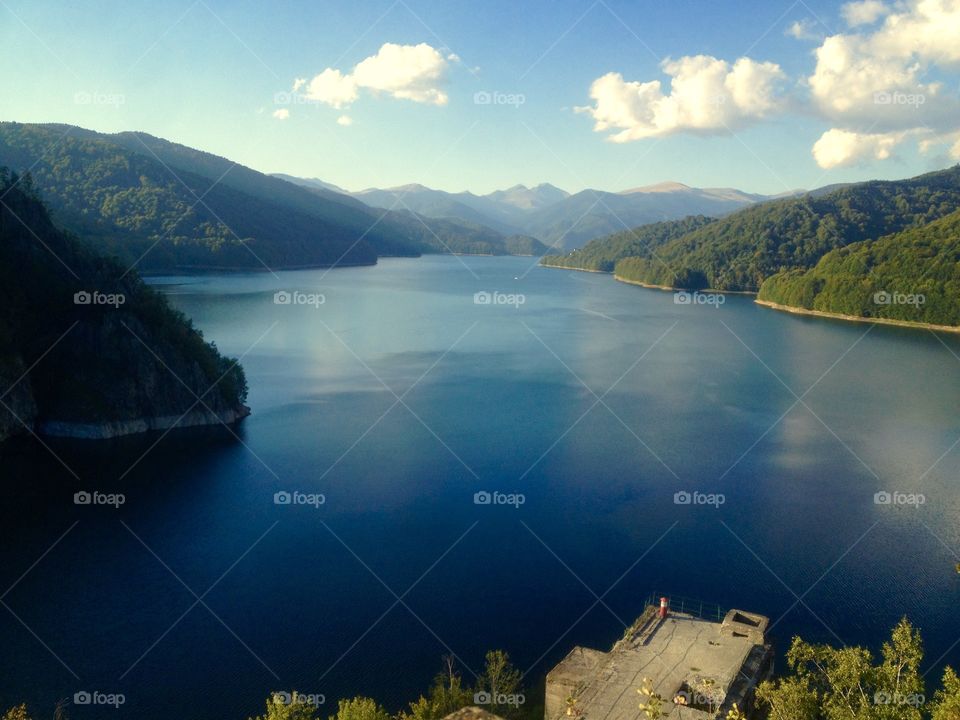 Blue water with forest around and blue sky