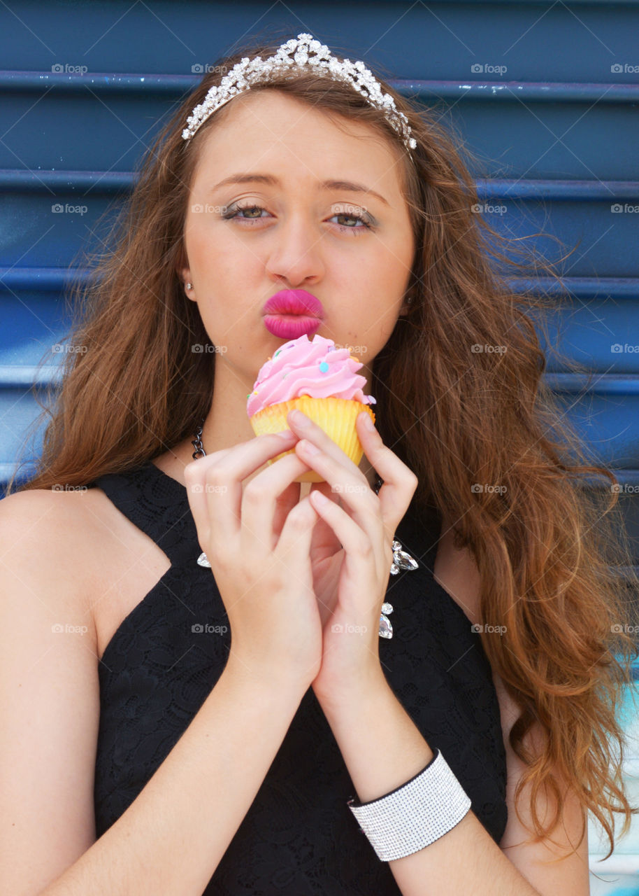 Portrait of a woman pouting with cupcake in had