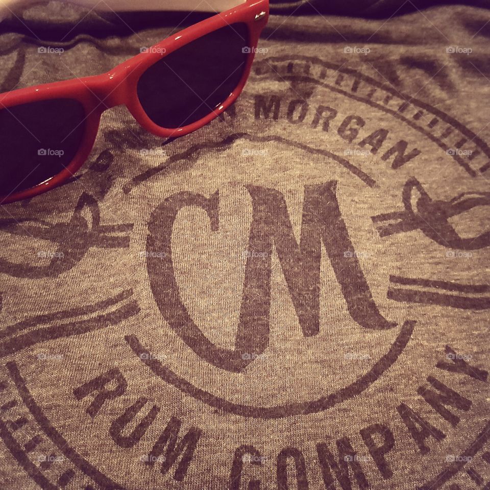 A Captain Morgan tshirt and sunglasses laid out for display.