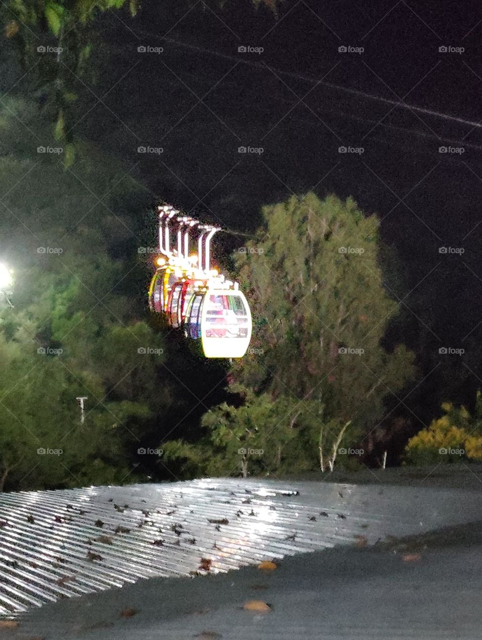 a night scene, looks roap way cabin,men and women with children are in the cabin of roap way green plant