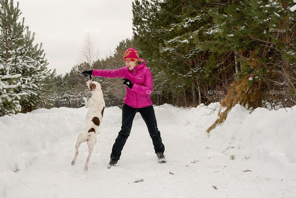 Young woman playing with dog on snow