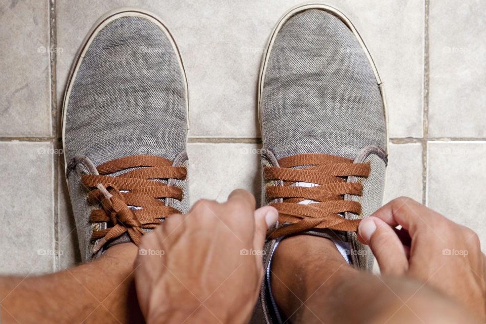 Young sportsman tying up tennis before going out to do running exercise in the morning
