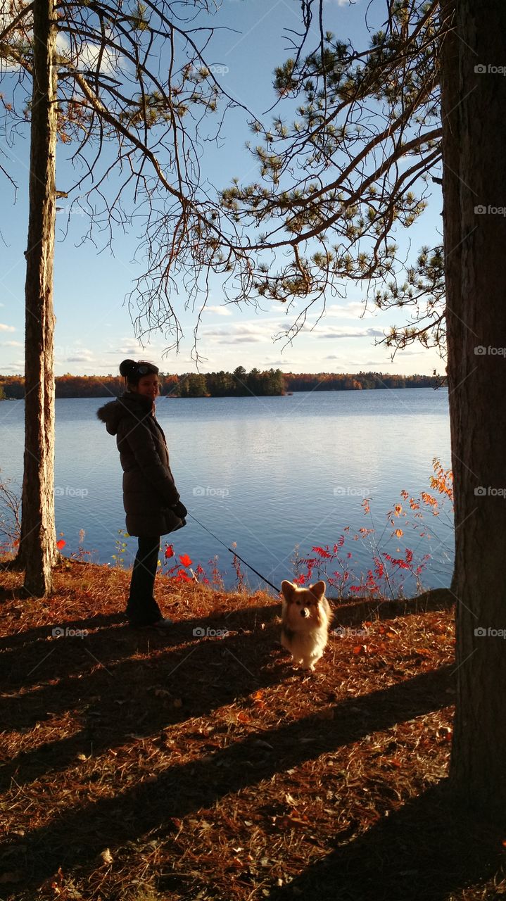 A teenage girl with dog standing near lake