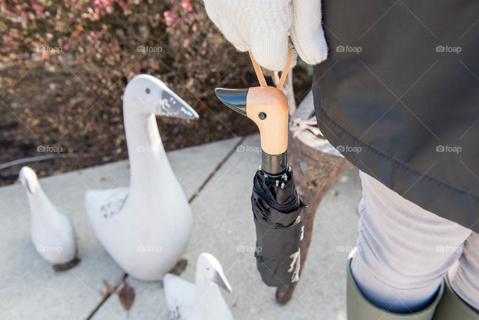 Close-up of a person holding a wooden duck head handle umbrella outdoors