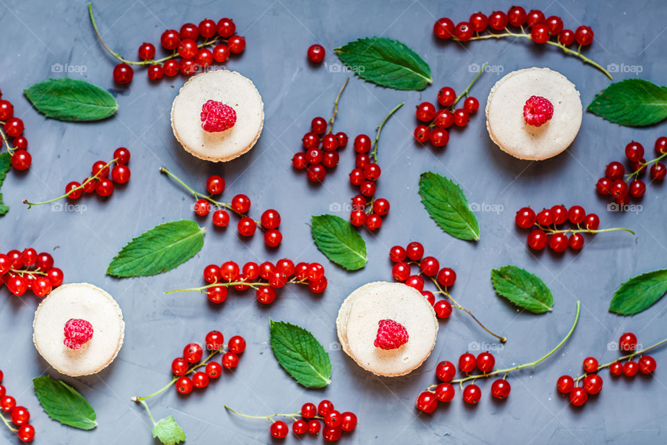 Fresh red currant, mint leaves, raspberry and macaroni on gray background 