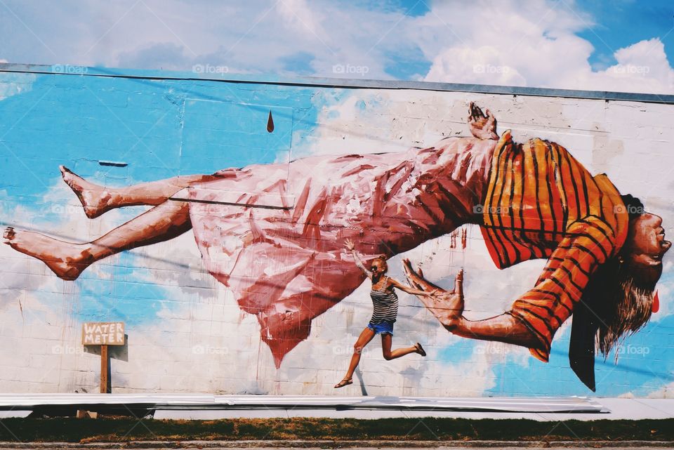 Woman jumping in front of painted wall