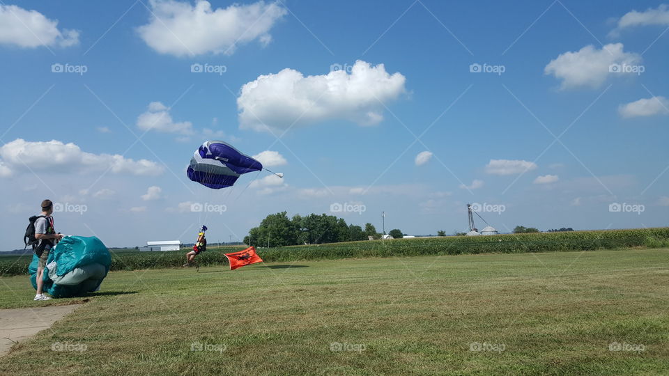 Parachuting man landing with a flag